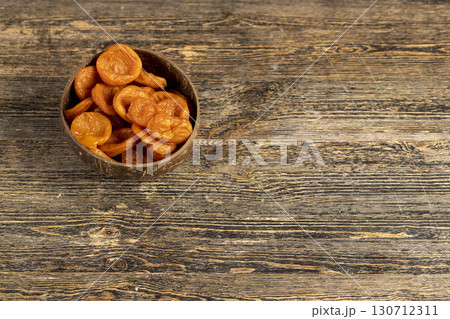 orange dried apricots made from apricots in a coconut shell plate, dried apricots in a bowl made from natural materials 130712311