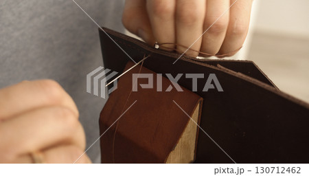 Artisan sewing handmade leather wallet by hand with strong needle Artisan sewing handmade leather wallet by hand with strong needle 130712462