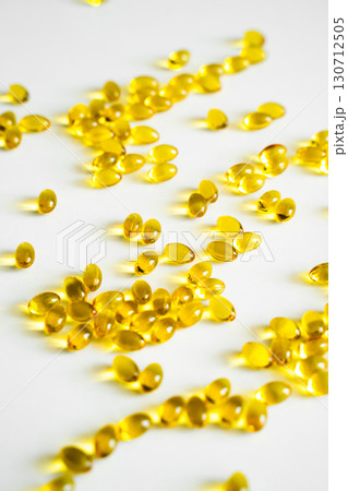 Bright yellow oval capsules scattered on white background, close-up of dietary supplements symbolizing vitamins, fish oil and healthcare Bright yellow oval capsules scattered on white background, close-up of dietary supplements symbolizing vitamins, fish oil and healthcare 130712505