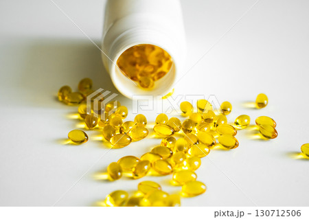 Golden yellow softgel capsules scattered on white background, dietary supplement with vitamins or fish oil in medical concept Golden yellow softgel capsules scattered on white background, dietary supplement with vitamins or fish oil in medical concept 130712506