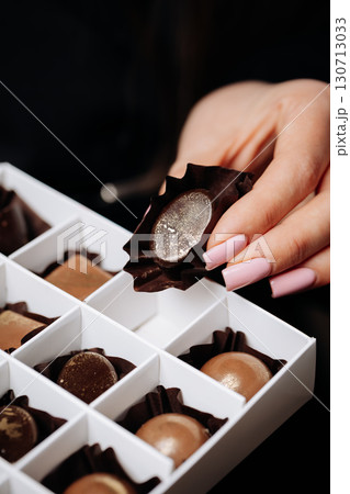 Luxury handmade chocolates in elegant box held by woman with manicured nails Luxury handmade chocolates in elegant box held by woman with manicured nails 130713033