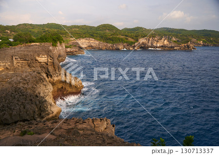 Cinematic aerial landscape shots of the beautiful island of Nusa Penida. Huge cliffs by the shoreline and hidden dream beaches with clear water and foaming wave. 130713337