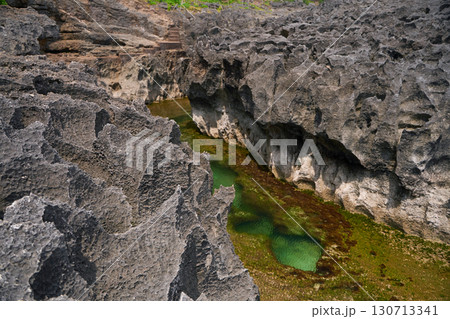 A cliff broken by the wave of the ocean. Natural azure bathing pool in the middle of the rock. A popular tourist spot on the island of Nusa Penida in Indonesia. A cliff broken by the wave of the ocean. Natural azure bathing pool in the middle of the rock. A popular tourist spot on the island of Nusa Penida in Indonesia. 130713341