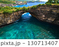 Rock broken by an ocean wave forming an arch in the mountain. Cliff is washed by powerful waves of ocean. Angel's Billabong is a popular tourist destination on the island of Nusa Penida in Indonesia. 130713407