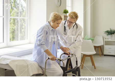 Woman using walker to walk with efforts in hospital, doctor training patient 130713552