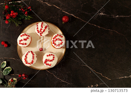 Winter background for greeting card. Curd muffins with glazed pomegranates with numbers 2026 in the form of a clock, an idea for decorating food and decorating New Year's dishes for children Winter background for greeting card. Curd muffins with glazed pomegranates with numbers 2026 in the form of a clock, an idea for decorating food and decorating New Year's dishes for children 130713573