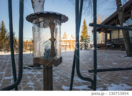 Wrought iron outdoor lantern with crackle glass, winter chalet and blue sky 130713954