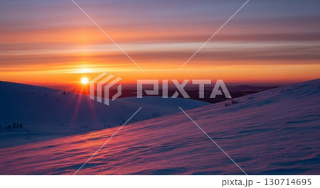 Majestic Winter Landscape at Sunset with Snow Covered Hills and Vibrant Orange Sky in Finland 130714695