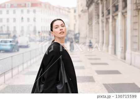 Young businesswoman in black coat standing on 130715599