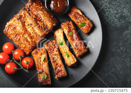 Hot grilled spare ribs from a summer BBQ served on a plate with sauce. Top view. Copy space Hot grilled spare ribs from a summer BBQ served on a plate with sauce. Top view. Copy space 130715875