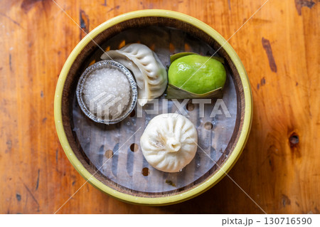 Assorted Asian Dumplings in Bamboo Basket on Wooden Table Assorted Asian Dumplings in Bamboo Basket on Wooden Table 130716590