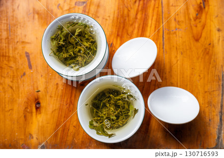 Traditional Green Tea Brewing in White Cups on Wooden Table 130716593