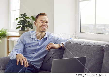 Portrait of a happy successful business man sitting on a sofa with his laptop computer Portrait of a happy successful business man sitting on a sofa with his laptop computer 130716684