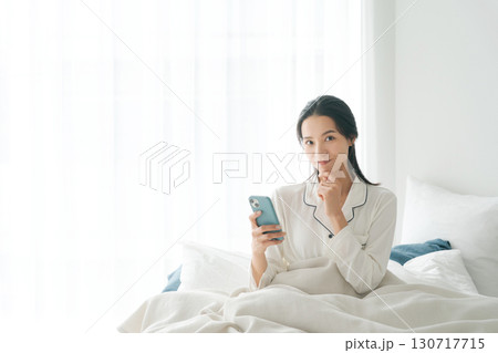 ベッドでスマホを操作する女性 130717715