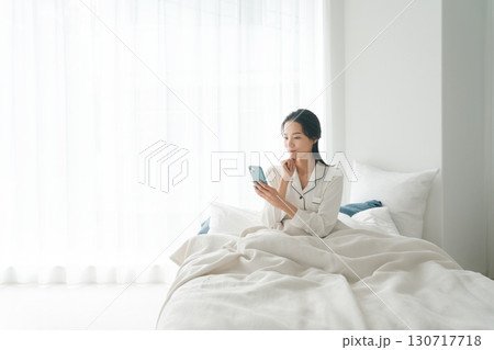 ベッドでスマホを操作する女性 130717718