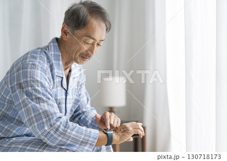 ベッドに座ってスマートウォッチを操作するシニア男性 ベッドに座ってスマートウォッチを操作するシニア男性 130718173