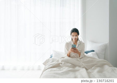 ベッドでスマホを操作する女性 ベッドでスマホを操作する女性 130718201