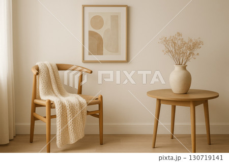 Scandinavian wooden chair with knitted blanket beside round wooden table holding ceramic vase with dried flowers under abstract wall art in soft natural light Scandinavian wooden chair with knitted blanket beside round wooden table holding ceramic vase with dried flowers under abstract wall art in soft natural light 130719141