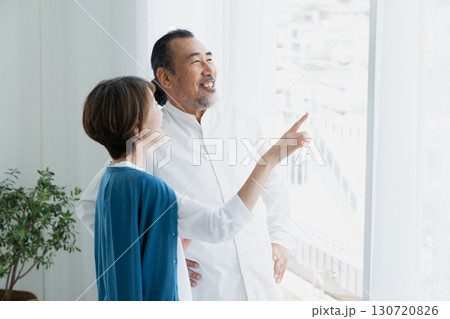 窓際で外を見るシニア夫婦 130720826
