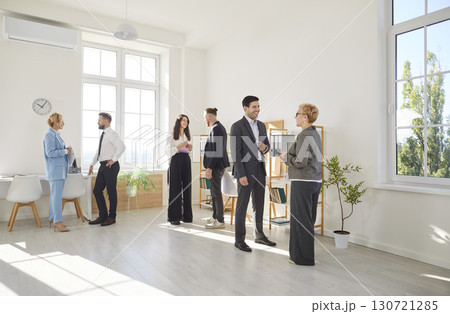 Diverse group of colleagues communicate and collaborate, creating friendly atmosphere in office. 130721285