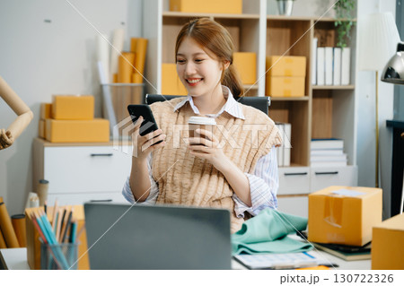 Young woman running online store Startup small business SME, using smartphone or tablet taking receive and checking 130722326