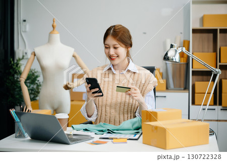 Young woman running online store Startup small business SME, using smartphone or tablet taking receive and checking 130722328