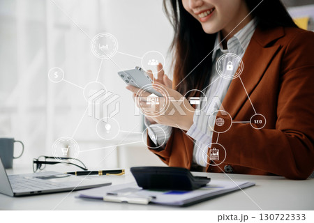 Designer woman using smart phone for mobile payments online shopping sitting on table,virtual icons Designer woman using smart phone for mobile payments online shopping sitting on table,virtual icons 130722333