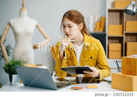 Young woman prepare parcel box and standing check online orders for deliver to customer on tablet, laptop Shopping Online concept. Young woman prepare parcel box and standing check online orders for deliver to customer on tablet, laptop Shopping Online concept. 130722335