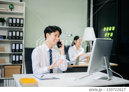 Two young Asian professionals engaged in teamwork and business discussions in modern office embodying corporate 130722627
