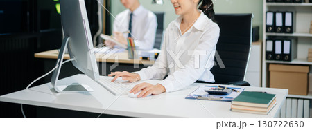 Two young Asian professionals engaged in teamwork and business discussions in modern office embodying corporate 130722630