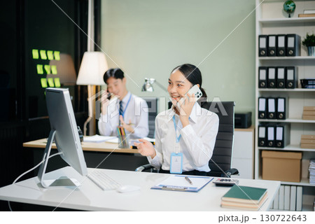 Two young Asian professionals engaged in teamwork and business discussions in modern office embodying corporate 130722643
