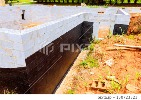 Workers are building foundation using concrete blocks, showcasing structure progress 130723523