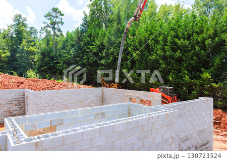 Construction workers are pouring concrete into newly built block foundation using concrete pump during constructed day 130723524