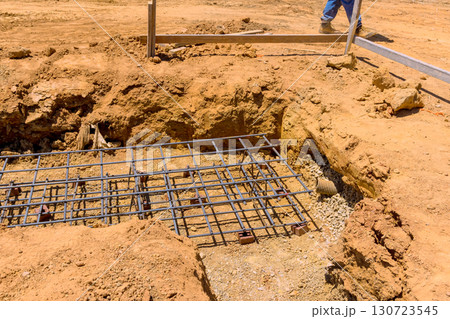 Construction workers engage in laying foundation with rebar freshly excavated soil at under construction work day Construction workers engage in laying foundation with rebar freshly excavated soil at under construction work day 130723545