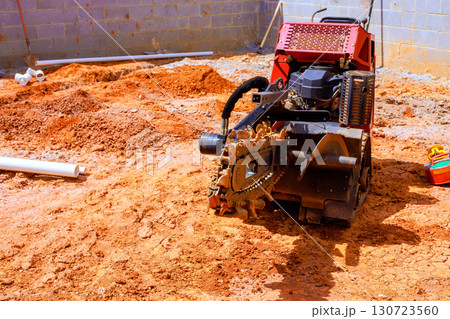 Heavy trench machinery operates on construction site, moving leveling dirt for new drainage system Heavy trench machinery operates on construction site, moving leveling dirt for new drainage system 130723560