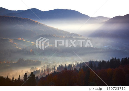 Misty autumn morning in mountain valley. Layers of hills bathed in soft light. 130723712