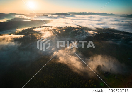 Aerial view of sunrise over mountainous landscape, with thick fog blanketing valleys and hills. Aerial view of sunrise over mountainous landscape, with thick fog blanketing valleys and hills. 130723718
