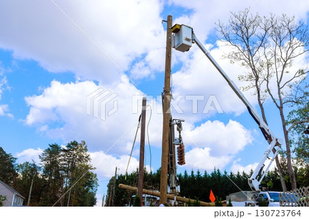 Electrical technician are using lifting platform to fix equipment on utility pole under works day 130723764