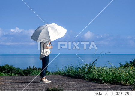 <素材>夏の海を眺める日傘の女性の後ろ姿 <素材>夏の海を眺める日傘の女性の後ろ姿 130723796