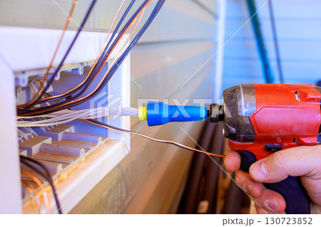 Electrician operates drill to connect wiring in residential exterior wall in broad works day Electrician operates drill to connect wiring in residential exterior wall in broad works day 130723852