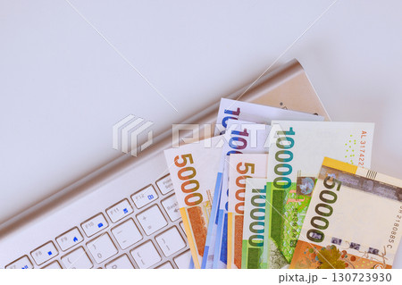 Various South Korean won currency notes placed alongside laptop keyboard highlight connection between money technology. 130723930