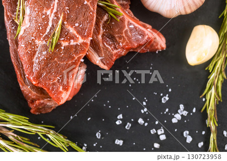 Juicy pieces of raw meat surrounded by garlic, fresh rosemary wait preparation for delicious barbecue. Juicy pieces of raw meat surrounded by garlic, fresh rosemary wait preparation for delicious barbecue. 130723958