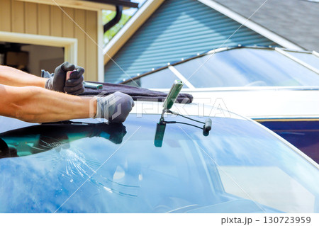Technician works on fixing cracked windshield at home, using specialized tools for glass replacement repair Technician works on fixing cracked windshield at home, using specialized tools for glass replacement repair 130723959