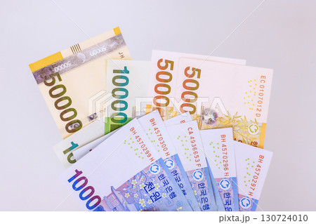 Various South Korean won banknotes of different values are arranged neatly on white surface, showcasing currency. 130724010