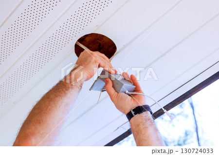 Contractor is installing ceiling fixture inside contemporary home during works day, focusing on task. 130724033