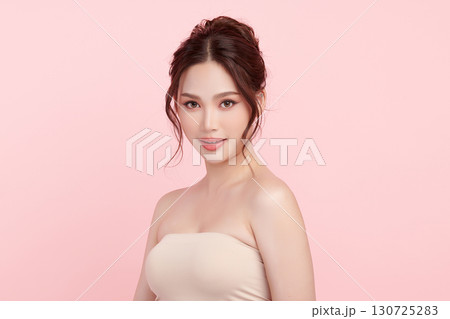 A beautiful young Asian woman with clean, fresh skin against a pink background. Skincare, facial treatment, cosmetology, beauty, and spa. An elegant portrait of an Asian woman. 130725283