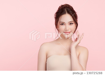 A beautiful young Asian woman with clean, fresh skin against a pink background. Skincare, facial treatment, cosmetology, beauty, and spa. An elegant portrait of an Asian woman. 130725288