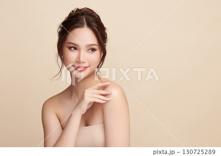 A beautiful young Asian woman with clean, fresh skin against a beige background. Skincare, facial treatment, cosmetology, beauty, and spa. An elegant portrait of an Asian woman. A beautiful young Asian woman with clean, fresh skin against a beige background. Skincare, facial treatment, cosmetology, beauty, and spa. An elegant portrait of an Asian woman. 130725289