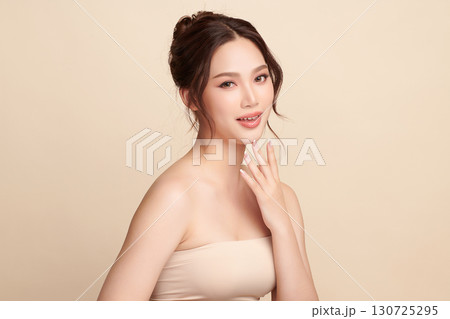 A beautiful young Asian woman with clean, fresh skin against a beige background. Skincare, facial treatment, cosmetology, beauty, and spa. An elegant portrait of an Asian woman. A beautiful young Asian woman with clean, fresh skin against a beige background. Skincare, facial treatment, cosmetology, beauty, and spa. An elegant portrait of an Asian woman. 130725295