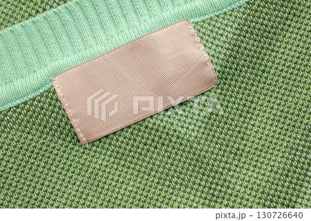 Brown blank laundry care clothes label on green shirt fabric background Brown blank laundry care clothes label on green shirt fabric background 130726640